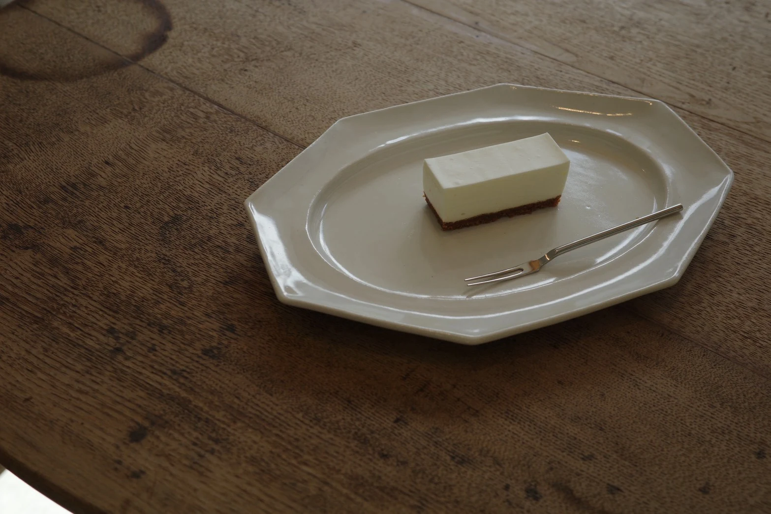 木のテーブルと白い器に盛り付けた喫茶白雫のレアチーズケーキ