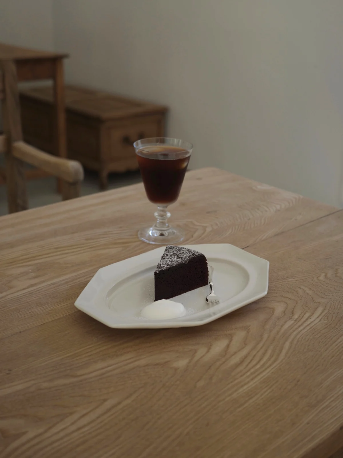 木のテーブルの白い器に盛り付けた喫茶白雫のショコラケーキと、グラスの飲み物