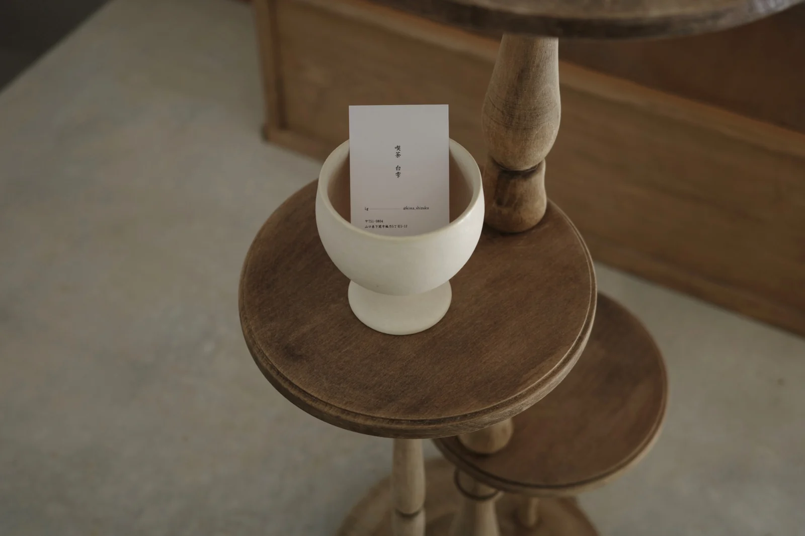木の棚と白い陶器に添えた喫茶白雫のショップカード